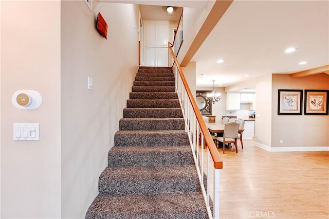 stairway featuring an inviting chandelier and hardwood / wood-style floors