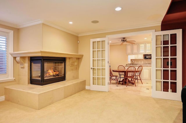 carpeted living room featuring french doors, a fireplace, sink, and crown molding