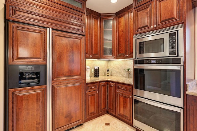 kitchen featuring tasteful backsplash, appliances with stainless steel finishes, and light stone counters