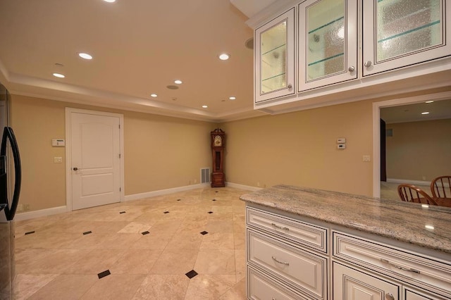 kitchen with a tray ceiling, light stone countertops, and light tile patterned floors