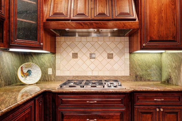 kitchen with backsplash, light stone countertops, custom range hood, and stainless steel gas stovetop