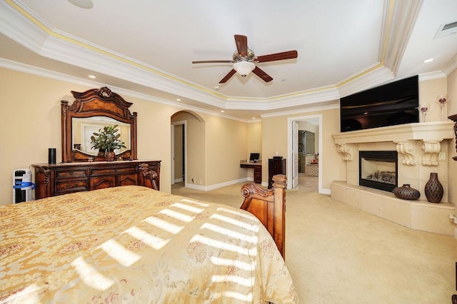 carpeted bedroom featuring a fireplace, ornamental molding, a raised ceiling, and ceiling fan