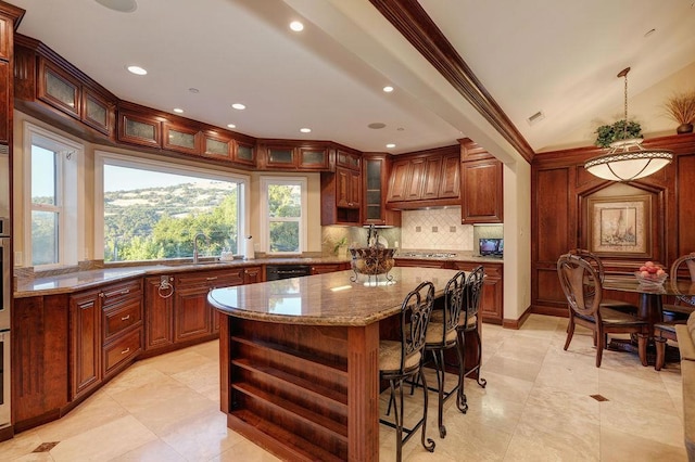 kitchen with a kitchen island, sink, stainless steel gas cooktop, light stone counters, and custom range hood