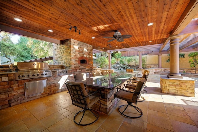 view of patio / terrace featuring a bar, ceiling fan, a grill, and exterior kitchen