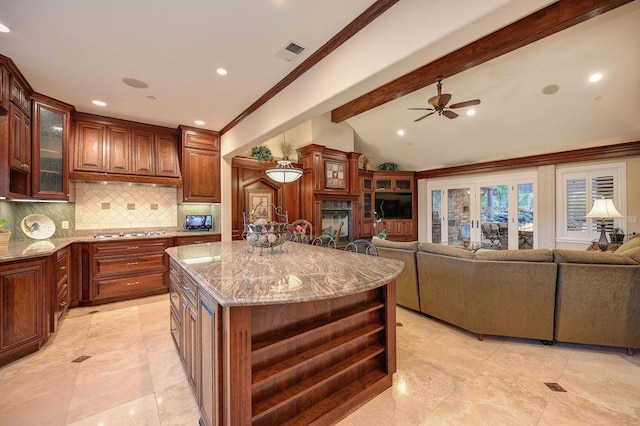 kitchen featuring a kitchen island, lofted ceiling with beams, backsplash, stainless steel gas cooktop, and light stone countertops