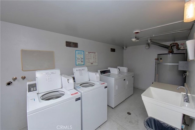 washroom with sink, washing machine and dryer, and water heater