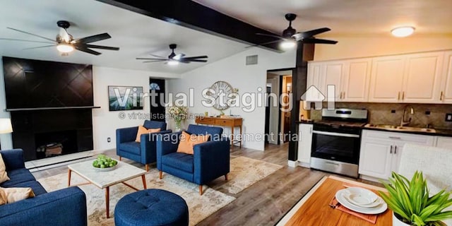 living room featuring vaulted ceiling with beams, sink, and light hardwood / wood-style flooring