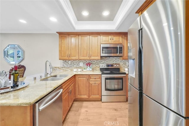 kitchen featuring sink, appliances with stainless steel finishes, tasteful backsplash, light hardwood / wood-style floors, and kitchen peninsula