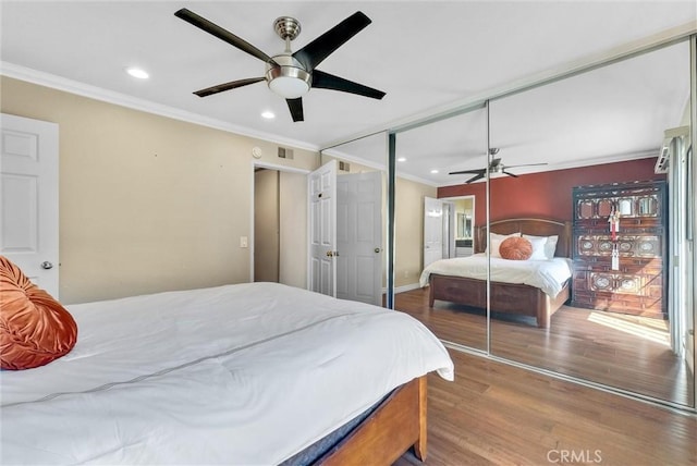 bedroom with a closet, ceiling fan, hardwood / wood-style floors, and crown molding