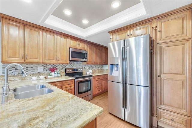 kitchen with light stone countertops, sink, stainless steel appliances, tasteful backsplash, and a tray ceiling