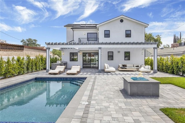 back of property featuring a patio area, a balcony, and an outdoor living space with a fire pit