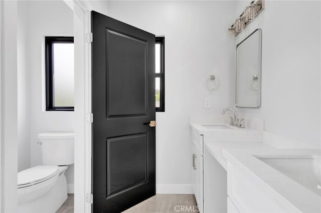 bathroom with wood-type flooring, vanity, and toilet