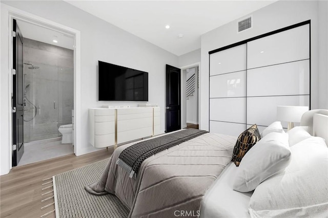 bedroom with ensuite bath and light hardwood / wood-style floors