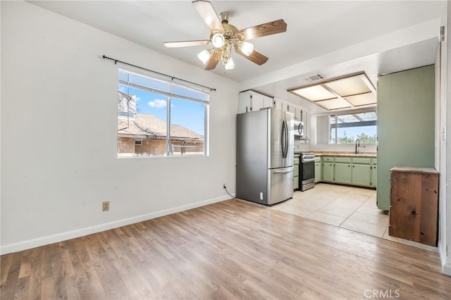 kitchen featuring appliances with stainless steel finishes, light hardwood / wood-style floors, green cabinetry, ceiling fan, and sink