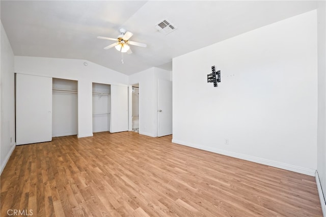 unfurnished bedroom featuring ceiling fan, multiple closets, light hardwood / wood-style flooring, and vaulted ceiling