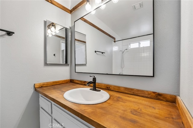 bathroom featuring vaulted ceiling, a shower, and vanity