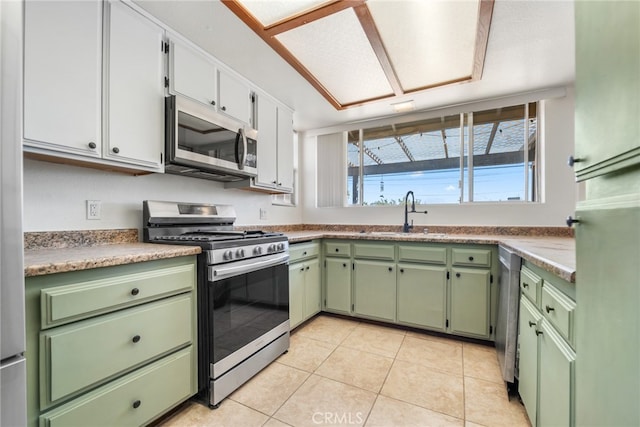 kitchen with sink, green cabinetry, white cabinetry, stainless steel appliances, and light tile patterned floors