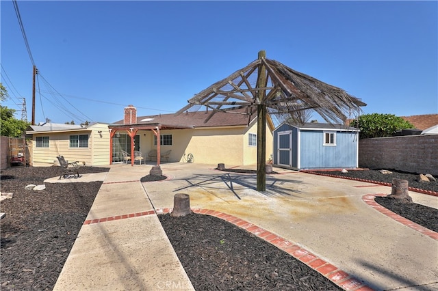 rear view of property with a storage unit and a patio area