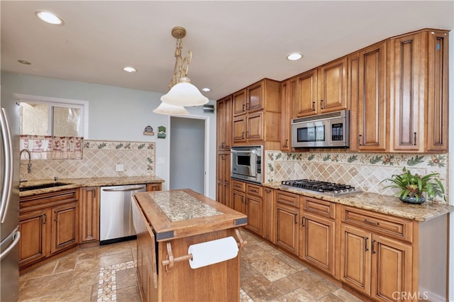 kitchen with decorative light fixtures, sink, light stone counters, stainless steel appliances, and backsplash