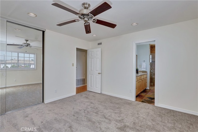 unfurnished bedroom featuring light carpet, a closet, ensuite bath, and ceiling fan