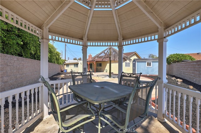 wooden terrace featuring a gazebo and a shed