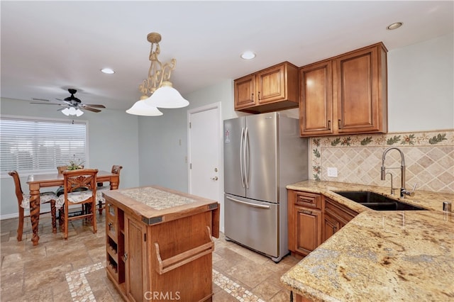 kitchen featuring stainless steel fridge, ceiling fan, pendant lighting, a kitchen island, and sink