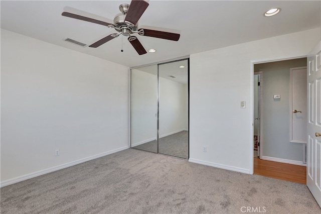 unfurnished bedroom featuring ceiling fan, a closet, and light carpet