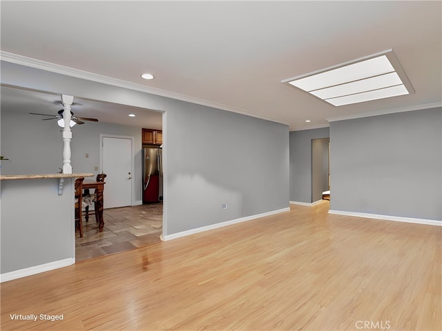 unfurnished room featuring ornamental molding, a skylight, and light hardwood / wood-style flooring