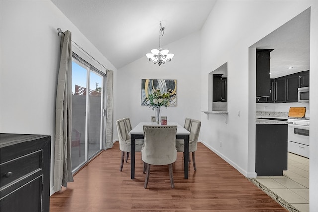 dining space with an inviting chandelier, lofted ceiling, and hardwood / wood-style floors