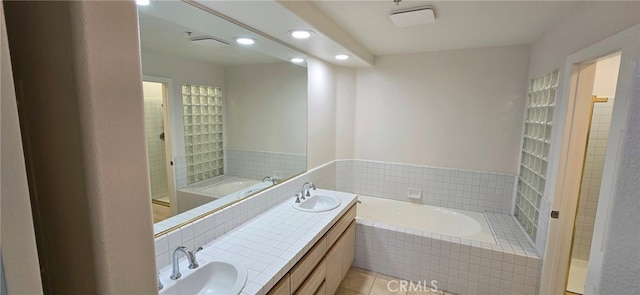 bathroom with vanity, tiled bath, and tile patterned flooring