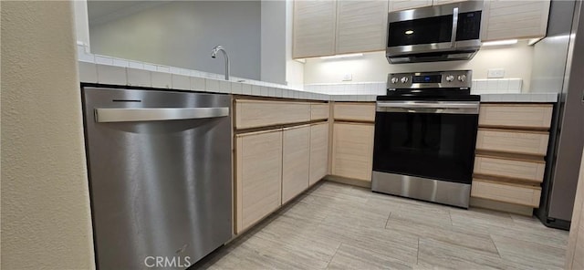 kitchen with appliances with stainless steel finishes, sink, and light brown cabinetry