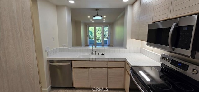 kitchen featuring appliances with stainless steel finishes, decorative light fixtures, light brown cabinetry, and sink