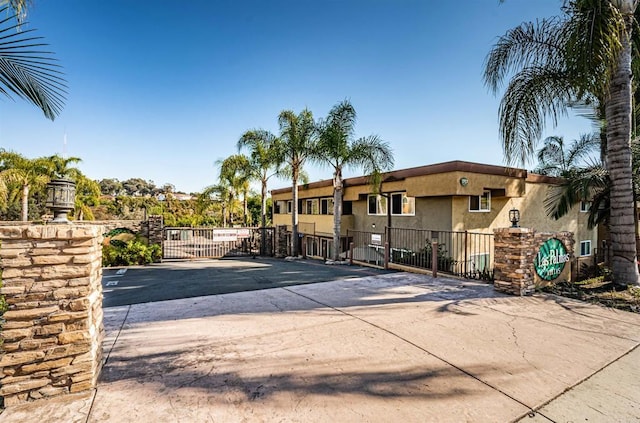 exterior space featuring stucco siding, fence, uncovered parking, and a gate