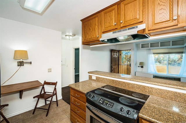 kitchen with tile patterned flooring, baseboards, under cabinet range hood, stainless steel electric range, and brown cabinetry