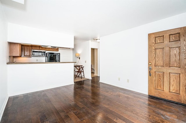 unfurnished living room with hardwood / wood-style flooring and baseboards