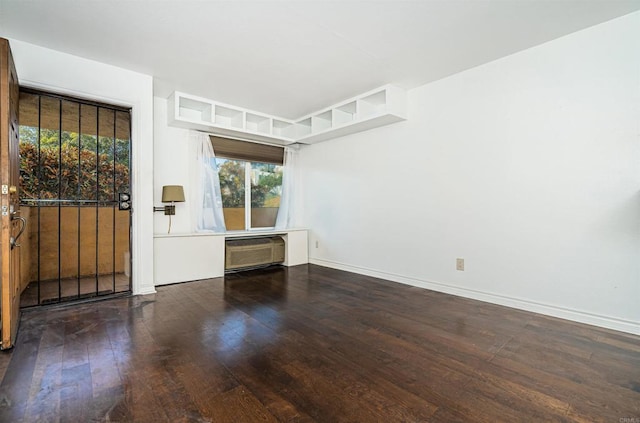 unfurnished room featuring a wall mounted AC, baseboards, and hardwood / wood-style flooring