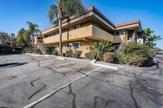 view of property with stairs and uncovered parking