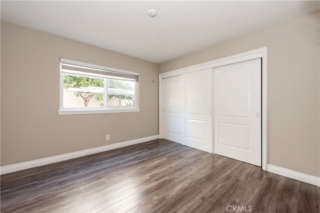 unfurnished bedroom featuring a closet and dark wood-type flooring