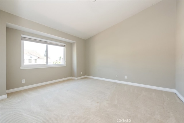 spare room with vaulted ceiling and light carpet