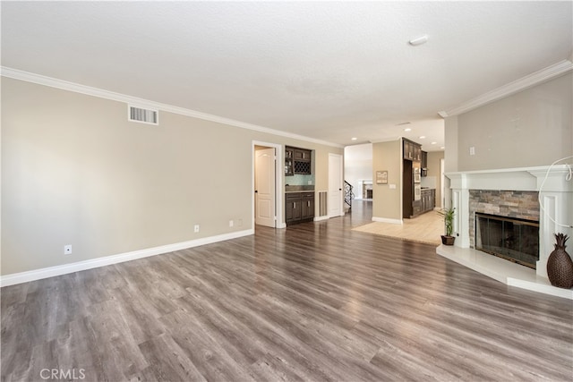 unfurnished living room featuring wood-type flooring, a stone fireplace, and ornamental molding