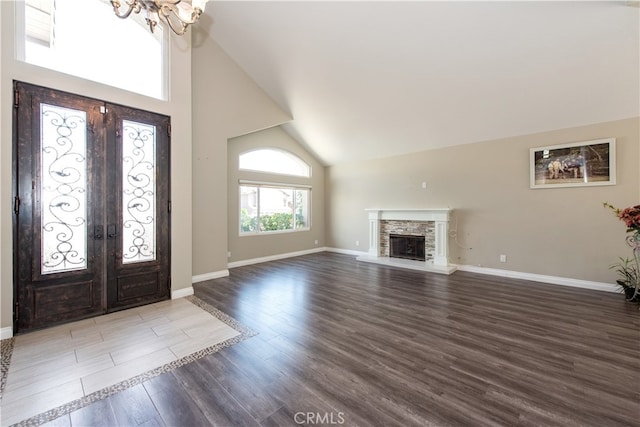 entryway with a fireplace, high vaulted ceiling, an inviting chandelier, hardwood / wood-style floors, and french doors