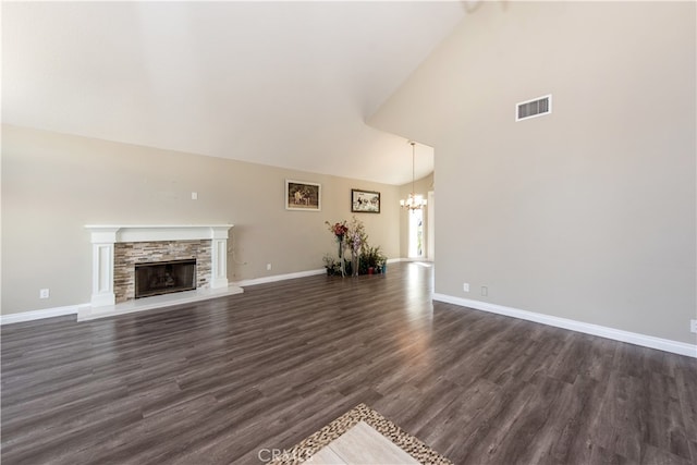 unfurnished living room with a notable chandelier, a stone fireplace, lofted ceiling, and dark hardwood / wood-style flooring