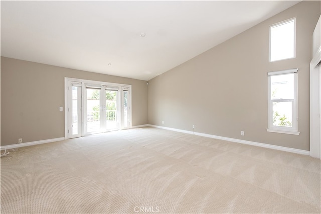 empty room with french doors, light colored carpet, and high vaulted ceiling