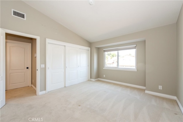 unfurnished bedroom with vaulted ceiling, a closet, and light colored carpet