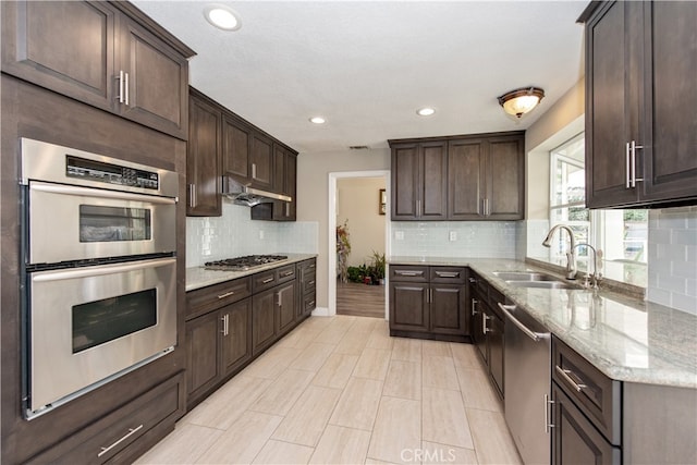 kitchen with appliances with stainless steel finishes, dark brown cabinets, and sink