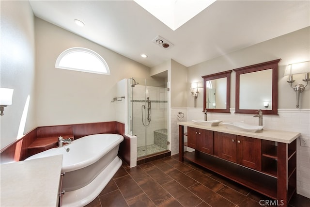 bathroom featuring tile walls, a skylight, vanity, and separate shower and tub