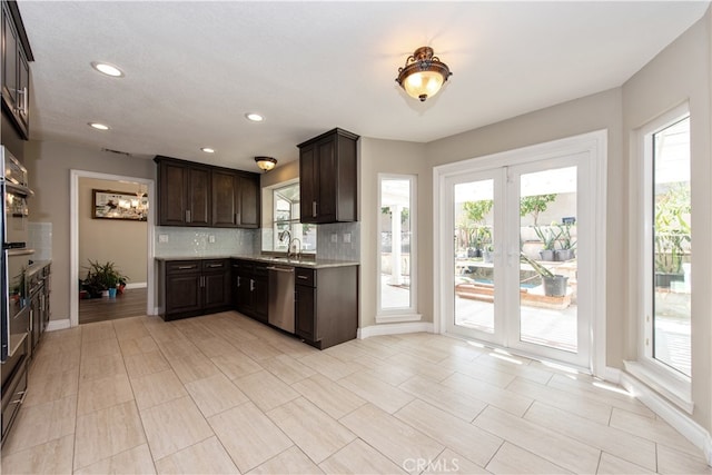 kitchen featuring appliances with stainless steel finishes, dark brown cabinetry, backsplash, and sink