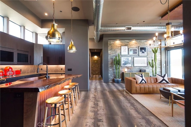 kitchen with sink, a high ceiling, a breakfast bar, dark hardwood / wood-style flooring, and decorative backsplash