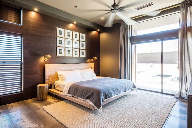 bedroom featuring wood walls, ceiling fan, and access to exterior