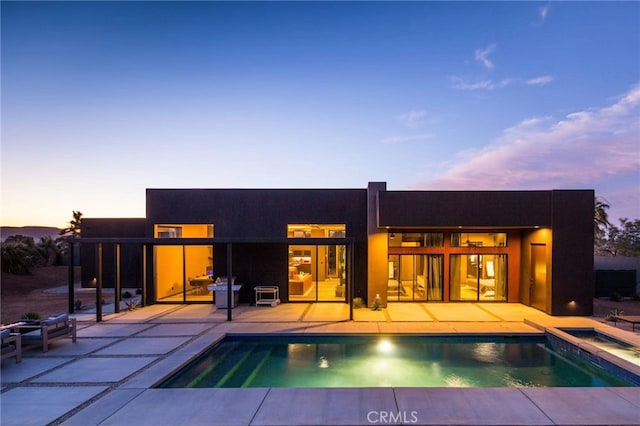 back house at dusk featuring a patio